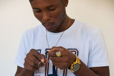 Portrait of man holding camera against wall