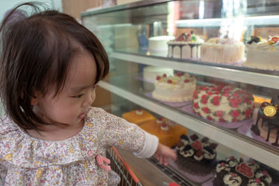 Close-up of cute baby girl looking at cakes in store