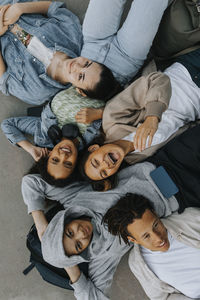 High angle view of smiling teenagers lying together and looking at camera