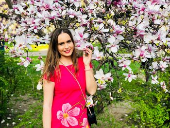 Beautiful woman by pink flowers growing on plant