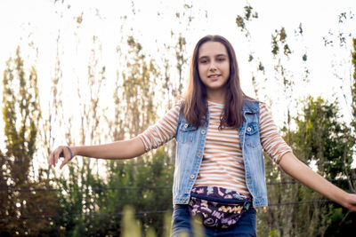 Portrait of young woman standing against trees