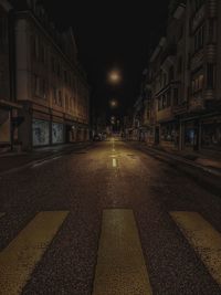 Surface level of road amidst buildings at night