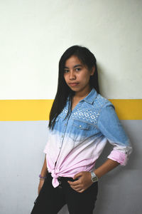 Portrait of woman standing against wall