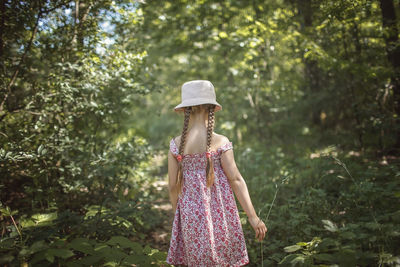 Woman wearing hat standing against trees