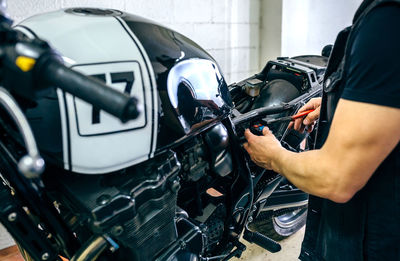 Midsection of man working on motorcycle in garage