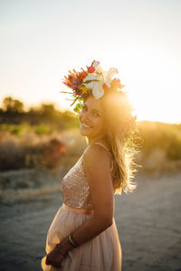 Portrait of woman wearing flowers walking at beach against sky