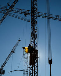 Low angle view of crane at construction site against clear sky