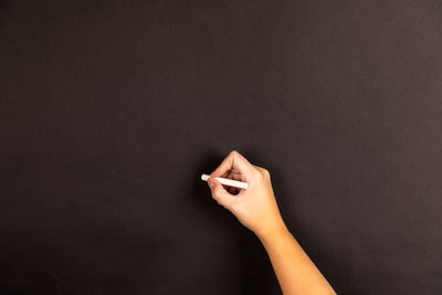 Person hand holding cigarette against black background