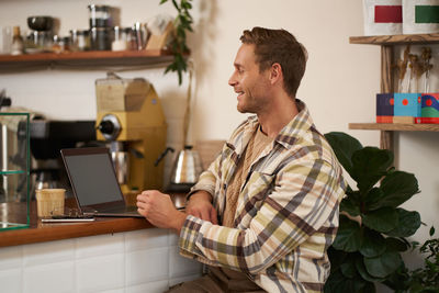 Side view of man using laptop while sitting on table