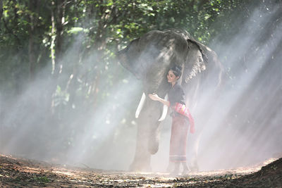 Young woman walking with elephant