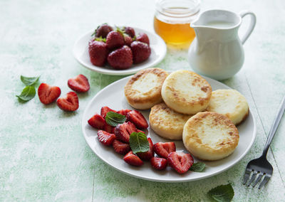 Cottage cheese pancakes, ricotta fritters on ceramic plate with fresh strawberry. 