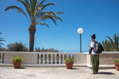 Man standing by palm trees against sky