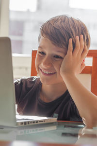 Smiling boy using laptop at table