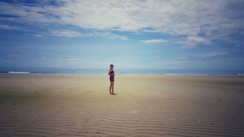 Rear view of person standing on beach against sky