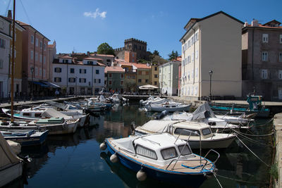 Boats moored at harbor by buildings in city