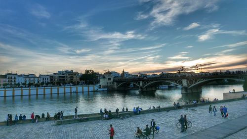 People on bridge over river against sky in sevilla city, triana bridge