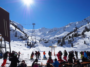 Skiers by snowcapped mountains against clear blue sky