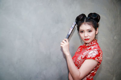 Portrait of beautiful woman standing against wall