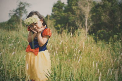 Portrait of cute girl wearing flowers while standing on grassy field
