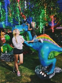 Full length of young woman standing by plants at night