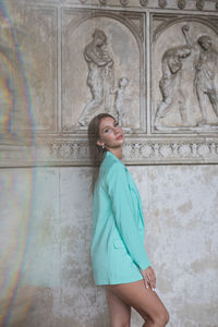 Young woman standing against wall