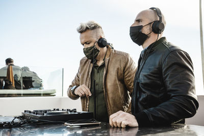 People working on table against sky