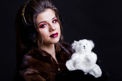 Young woman with toy against black background