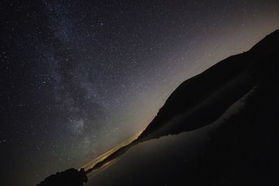 Low angle view of silhouette mountain against sky at night