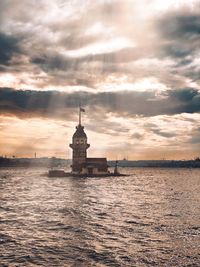 View of building by sea against cloudy sky