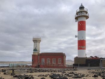 Low angle view of lighthouse by building against sky