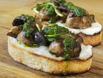 Close-up of bruschetta served with champignons and spinach on cutting board