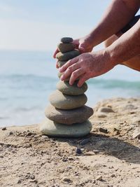 Man stacking pebbles on shore at beach