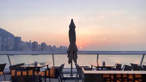 Rear view of building by sea against sky during sunset