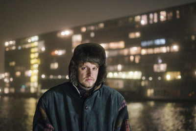 Portrait of young man standing in city at night