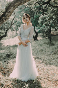 Portrait of woman with arms outstretched against trees