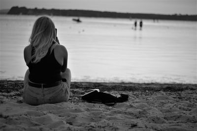 Rear view of woman sitting on beach