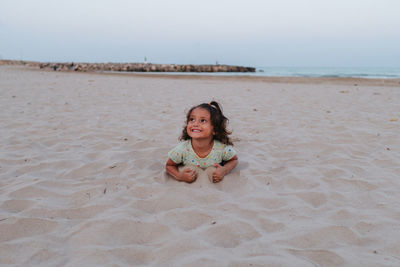Smiling girl, lying on the sand on the beach
