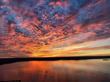 Scenic view of lake against dramatic sky during sunset