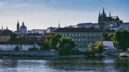 Buildings by river against clear sky