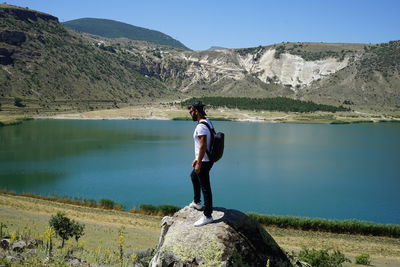 Full length of man standing on lake against mountain