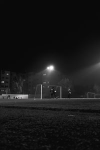 Surface level of soccer field against sky at night