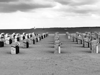 Hooded chairs on beach against sky