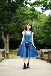 Young woman standing on footpath against trees