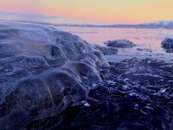 Close-up of sea shore against sky during sunset