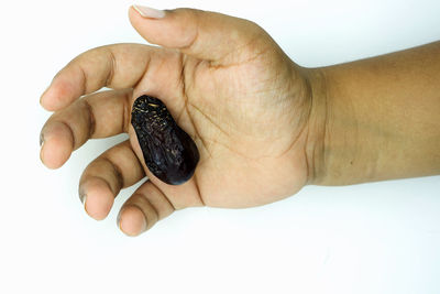 Close-up of human hand holding chocolate over white background
