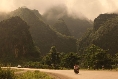 Man riding motorcycle on road against mountains