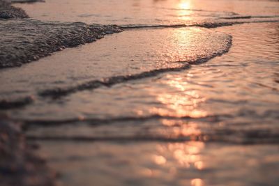 Surface level of beach against sky during sunset