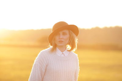 Close-up of young woman standing on grass field during sunset