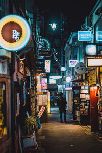 Rear view of people on illuminated street at night