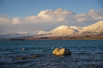 Scenic view of lake and snowcapped mountains against sky